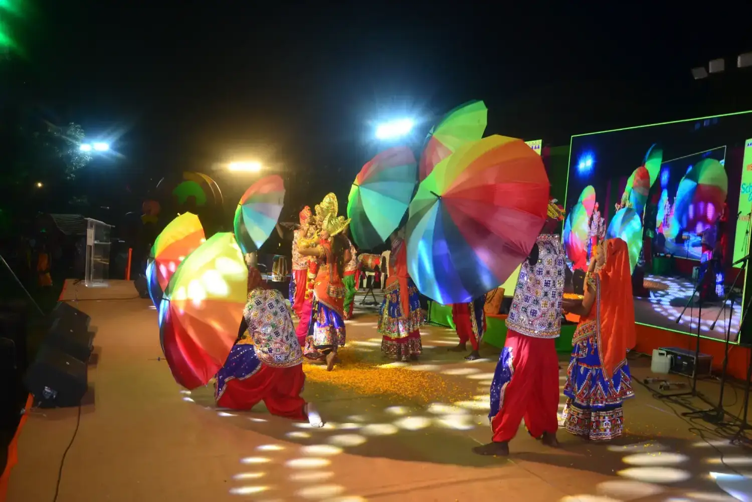 Man and woman speaking on stage at night with blue lighting